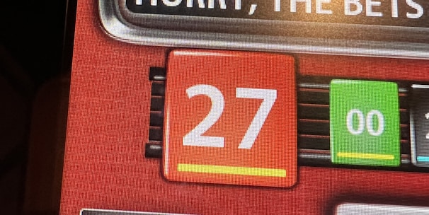 A digital display screen showing a casino betting interface, with text prompting to hurry bets and a highlighted number 27 in red. There are options for betting amounts and a 'share bets' button.